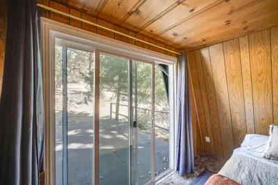 a bedroom with sliding glass doors in a wooden wall at Quiet Sequoia National Forest Cabin with Fireplace in Posey