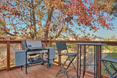 a grill on a deck with two chairs and a table with a laptop at Bethel Island Sanctuary with Dock and Boathouse in Oakley