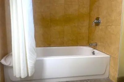 a white bath tub with a shower curtain in a bathroom at Sunstar Inn Los Banos near I-5 in Los Banos