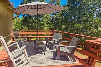 a wooden deck with chairs and an umbrella at Redwood Escape in Arnold