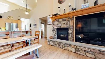 a living room with a stone fireplace and a tv at Mammoth Green #214 condo in Mammoth Lakes