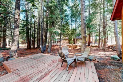 two chairs and a table on a wooden deck in the woods at Truckee Mountain Retreat in Truckee