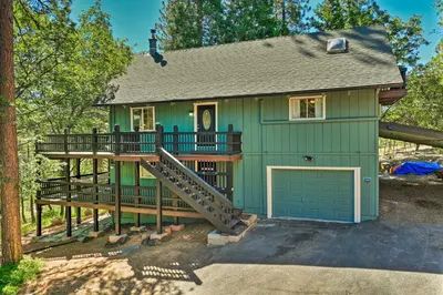 a green house with a deck and a garage at Near Trails Cabin with 2-Level Deck in Twain Harte in Twain Harte