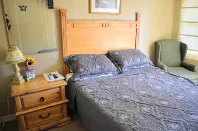 a bedroom with a bed and a dresser with a lamp and a chair at Genas's Sierra Inn & Restaurant in Dunlap