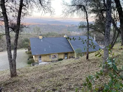 a yellow house on a hill with trees at Sierra Ranch - A Yosemite Retreat in Mariposa