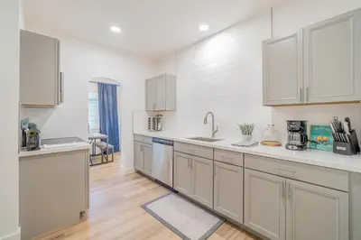 a kitchen with white cabinets and wooden floors at Plush 2-bed apt in Riverside Heights! in Reno