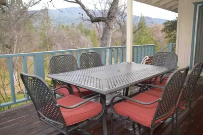 a table and chairs on a porch with a view at Beautiful 3 bedroom home located near Yosemite in Oakhurst