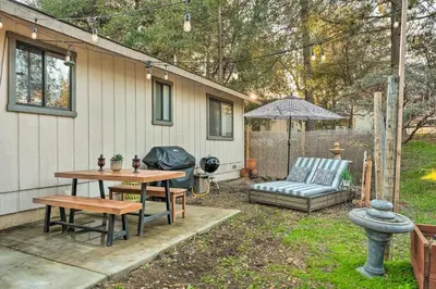 a patio with a table and a bench and an umbrella at Lakeside Groveland Home with Hot Tub, Near Yosemite in Groveland
