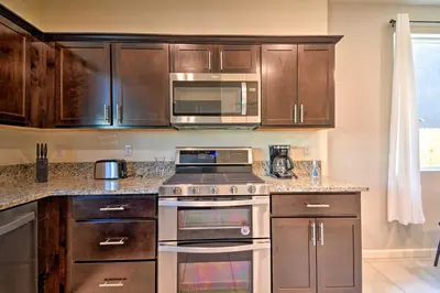 a kitchen with stainless steel appliances and wooden cabinets at 4 Mi to City Center Family-Friendly Retreat! in Merced