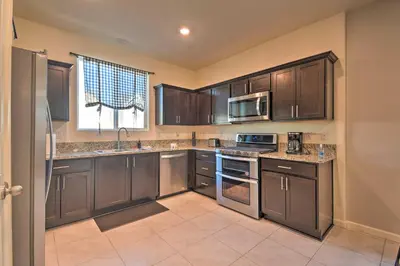 a kitchen with brown cabinets and a sink and a microwave at 4 Mi to City Center Family-Friendly Retreat! in Merced