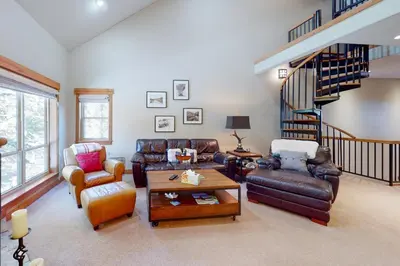 a living room with leather furniture and a spiral staircase at Snow Porch in Truckee