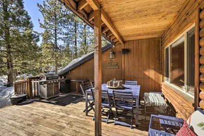 a wooden deck with a table and a grill at Dog-Friendly Kings Beach Log Cabin with Hot Tub! in Kings Beach