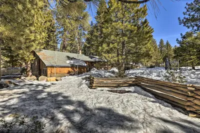 a log cabin in the snow next to a fence at Dog-Friendly Kings Beach Log Cabin with Hot Tub! in Kings Beach