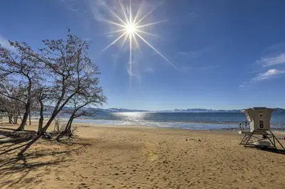 a beach with a lifeguard tower and the sun at Dog-Friendly Kings Beach Log Cabin with Hot Tub! in Kings Beach