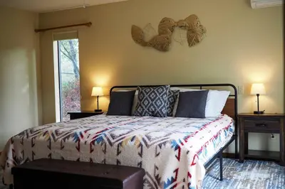 a bedroom with a bed and two lamps and a window at Yosemite Riverside Retreat with small beach access and air conditioning in Oakhurst