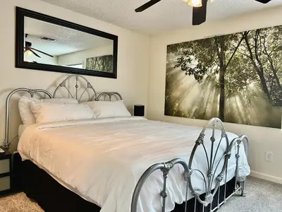 a bedroom with a bed with a large painting on the wall at DT Reno - 4BR Home with Patio, BBQ Grill, Games Room in Reno
