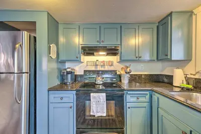 a kitchen with blue cabinets and a stove top oven at Walk Downtown Arnold Cabin with Large Deck! in Arnold