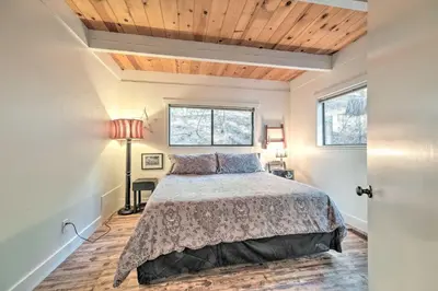 a bedroom with a bed and two windows at Walk Downtown Arnold Cabin with Large Deck! in Arnold