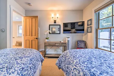 a bedroom with two beds and a table and a mirror at Furnished Deck Cabin on Northstar Shuttle Route! in Truckee