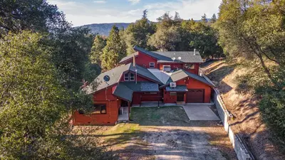 an aerial view of a red house in the woods at Red Oasis in Oakhurst