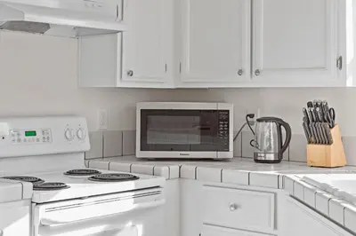 a white kitchen with white cabinets and a microwave at Delightful 4BR Home Nr Downtown Reno w Fireplace in Reno