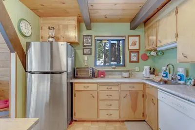 a kitchen with a stainless steel refrigerator and wooden cabinets at Popular A-frame Cabin With Deck & Views - Vh 216 in Bear Valley