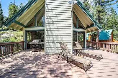 a house with two chairs and a grill on a deck at Spacious Cabin Sleeps up to 12 - Sky High #86 in Bear Valley