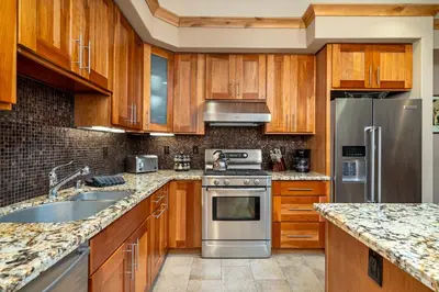 a kitchen with wooden cabinets and stainless steel appliances at Modern Condo - Jacuzzi Tub SM #201 in Bear Valley
