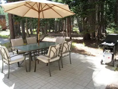 a table and chairs with an umbrella and a grill at Great Location Corner Condo - Tamarack #10 Pets Ok in Bear Valley