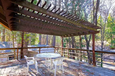a wooden patio with a table and chairs on a deck at Lancaster Cabin in Bass Lake
