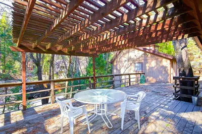 a patio with a table and chairs on a deck at Lancaster Cabin in Bass Lake