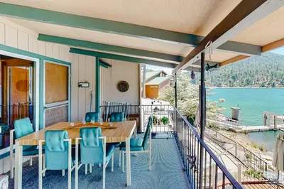 a porch with a wooden table and chairs on a balcony at Paha Lakefront in Bass Lake