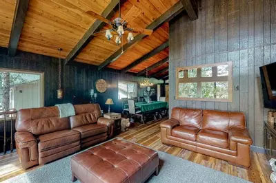 a living room with leather furniture and wooden walls at Twets Lakefront in Bass Lake