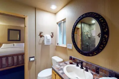 a bathroom with a sink and a toilet and a mirror at Yosemite Silvertip Lodge in Fish Camp