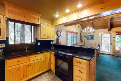 a large kitchen with wooden cabinets and black counter tops at Yosemite Silvertip Lodge in Fish Camp