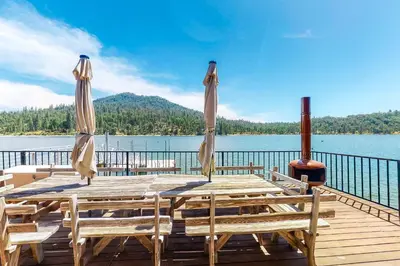 a wooden table with chairs and umbrellas on a dock at Peters Lakefront in Bass Lake