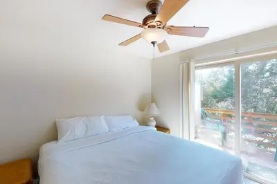 a bedroom with a ceiling fan and a bed with a window at Streiff Lake House in Bass Lake