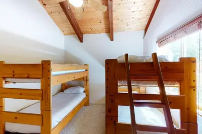 two bunk beds in a room with wooden ceilings at Streiff Lake House in Bass Lake