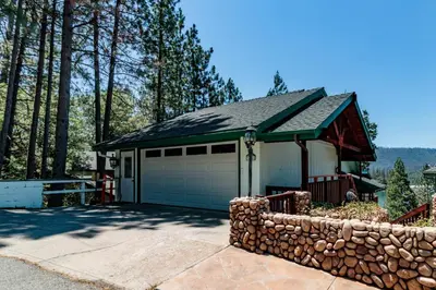 a house with a garage and a stone wall at Knott Lakeview in Bass Lake
