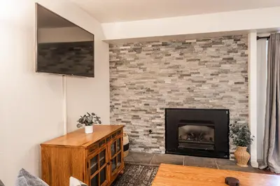 a living room with a brick fireplace with a tv at Warm and cozy upgraded 2 bedrm 2 bath single level condo in Snowcreek complex phase IV 563 Sleeps 6 in Mammoth Lakes