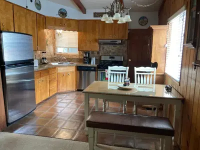 a kitchen with wooden cabinets and a table with chairs at Kernville - walk to River Kern & Downtown in Kernville