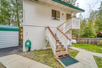 a white house with a staircase next to a garage at Black Bear Cabin in Bass Lake