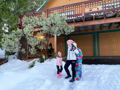 a woman and a child holding a snowboard in the snow at Bearvista in Arnold