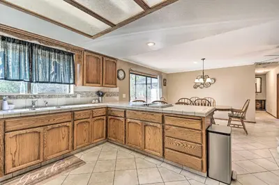 a large kitchen with wooden cabinets and a table at Deck and Hot Tub Rustic Groveland Home! in Groveland