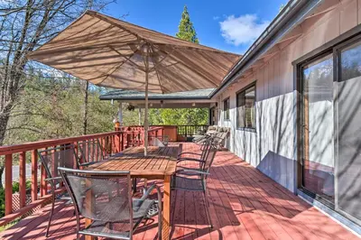 a deck with a wooden table and chairs and an umbrella at Deck and Hot Tub Rustic Groveland Home! in Groveland