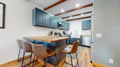 a kitchen with blue cabinets and a counter with stools at Val DIsere 32 Pet-Friendly, Walk To The Village, Private Washer Dryer, Spacious Floorplan condo in Mammoth Lakes