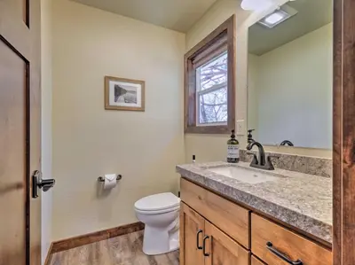 a bathroom with a toilet and a sink and a window at Woodsy Retreat Modern Mi-Wuk Village Cabin! in Mi-Wuk Village