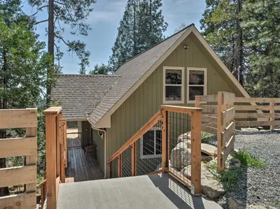 a small green building with a wooden fence at Woodsy Retreat Modern Mi-Wuk Village Cabin! in Mi-Wuk Village