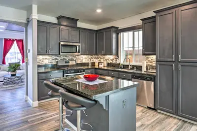 a kitchen with black cabinets and a island with a bowl on the counter at Modern Sacramento House about 12 Mi to Downtown! in Sacramento