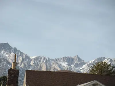 a snow covered mountain in the distance behind a house at Lone Pine Budget Inn in Lone Pine